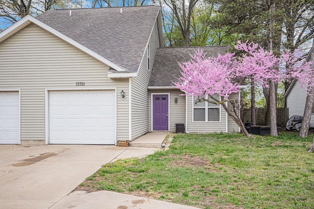 view of front facade featuring roof with shingles, a front yard, a garage, and driveway