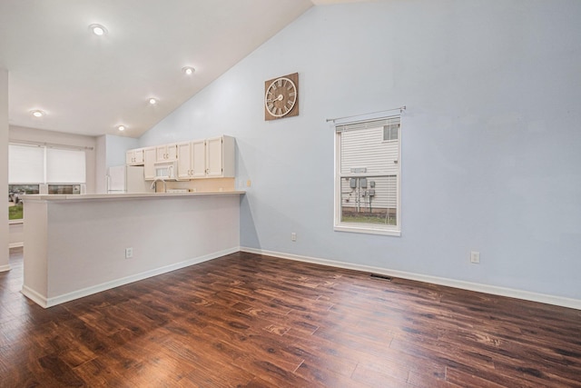unfurnished living room with baseboards, dark wood-style flooring, and high vaulted ceiling