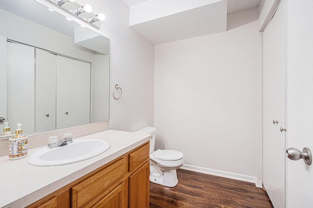 bathroom with toilet, baseboards, wood finished floors, and vanity