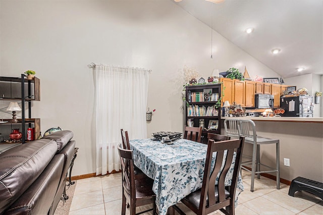 dining area featuring baseboards, lofted ceiling, and light tile patterned flooring