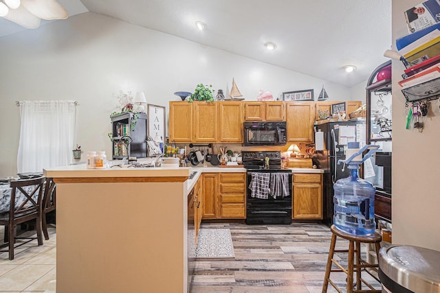 kitchen featuring a peninsula, high vaulted ceiling, black appliances, light countertops, and light wood-type flooring