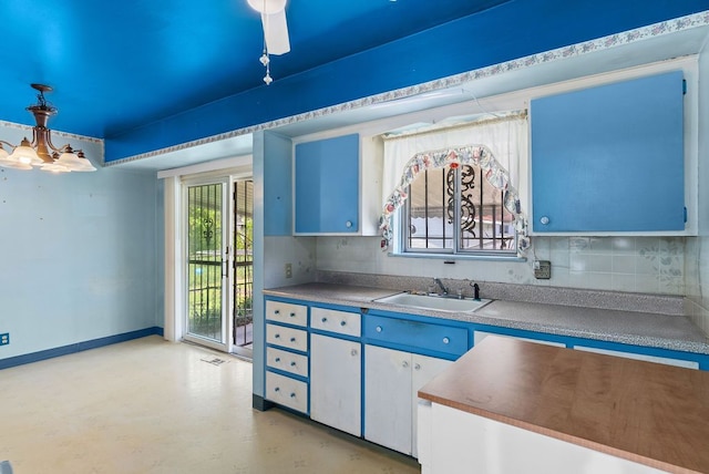 kitchen with a sink, decorative backsplash, baseboards, and pendant lighting