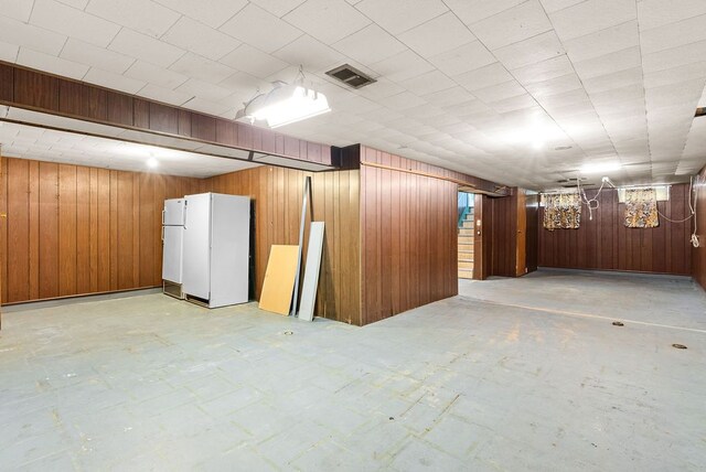 finished below grade area featuring wooden walls and freestanding refrigerator