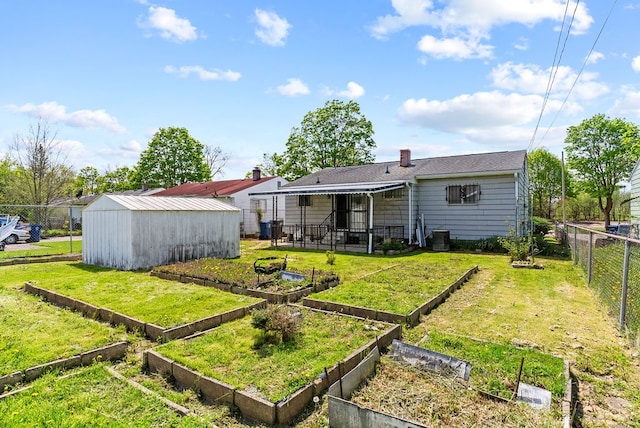 rear view of property with a garden, a chimney, and an outbuilding