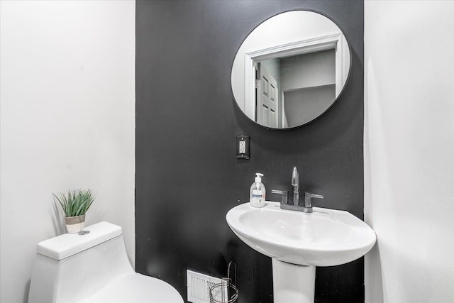 bathroom featuring a sink, toilet, and visible vents