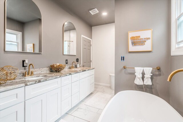 bathroom with marble finish floor, a wealth of natural light, a sink, a soaking tub, and double vanity