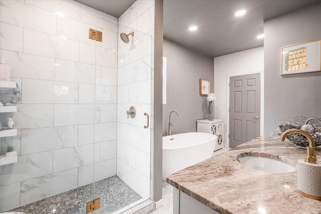 bathroom with recessed lighting, vanity, a stall shower, and a freestanding tub