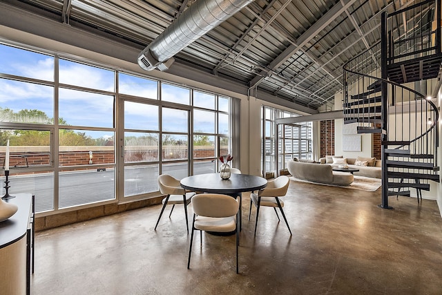 sunroom / solarium featuring high vaulted ceiling and concrete floors