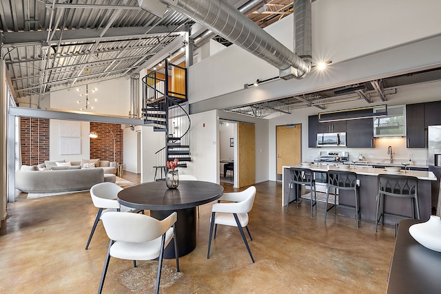 dining room with finished concrete flooring, a high ceiling, and stairway