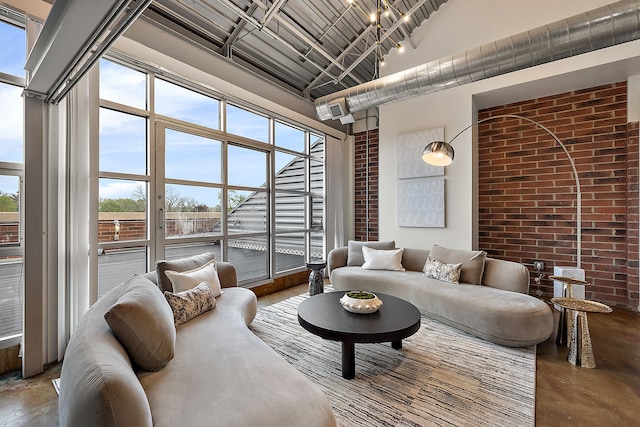 living room with brick wall, a high ceiling, and concrete floors