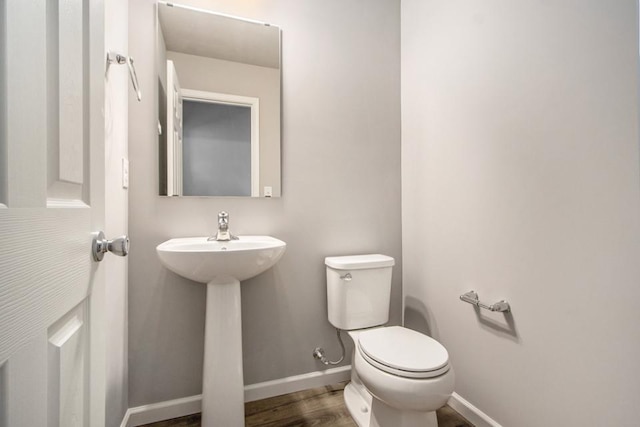 bathroom with toilet, baseboards, and wood finished floors