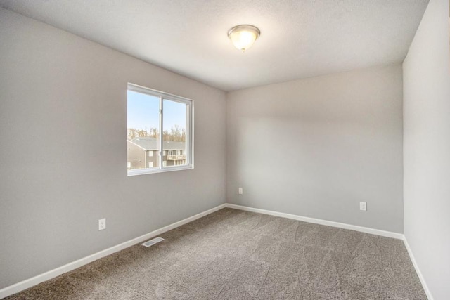 empty room with baseboards, visible vents, and carpet floors