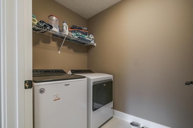 washroom featuring washer and clothes dryer, laundry area, and a textured ceiling