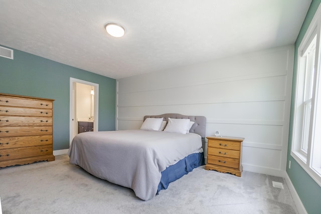 bedroom featuring carpet, ensuite bath, visible vents, and baseboards