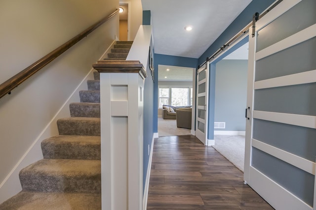 staircase featuring recessed lighting, a barn door, baseboards, visible vents, and wood finished floors