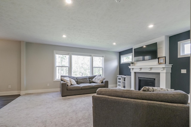 carpeted living area featuring a large fireplace, a wealth of natural light, baseboards, and recessed lighting