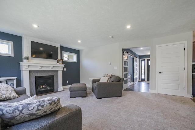 living area featuring a fireplace, carpet flooring, a barn door, and recessed lighting