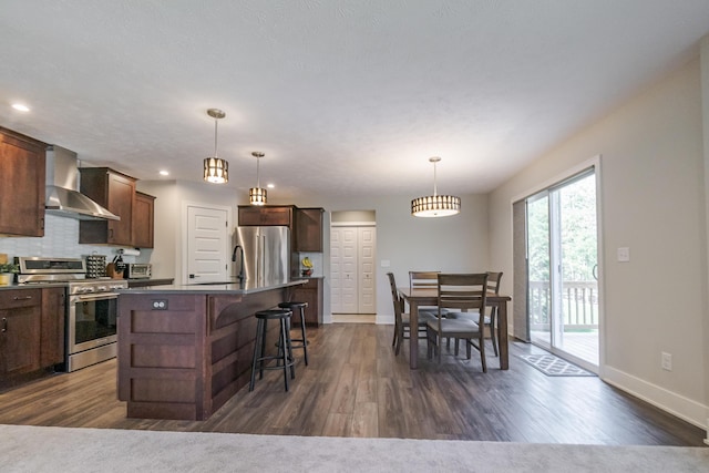 kitchen with baseboards, wall chimney range hood, dark wood finished floors, and appliances with stainless steel finishes