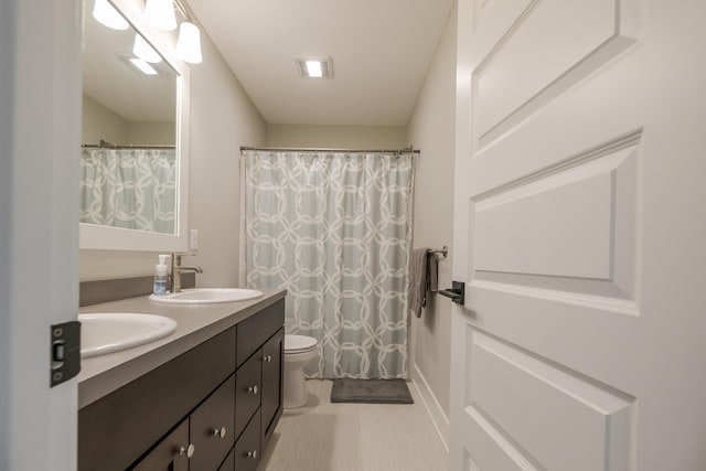 bathroom featuring toilet, double vanity, and a sink