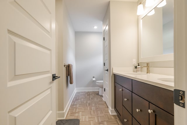 full bath featuring double vanity, toilet, a sink, baseboards, and recessed lighting