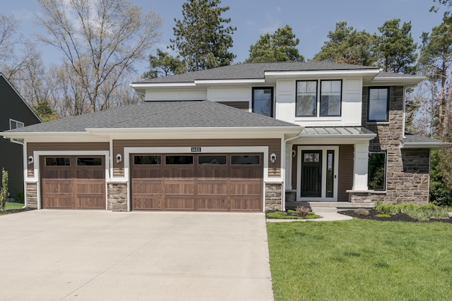 prairie-style house with a standing seam roof, a garage, concrete driveway, stone siding, and a front lawn