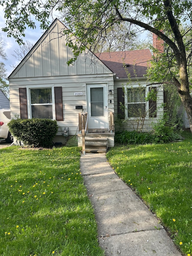 bungalow featuring a chimney and a front lawn