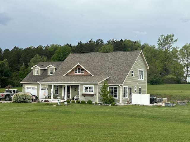 new england style home featuring covered porch, a shingled roof, and a front yard