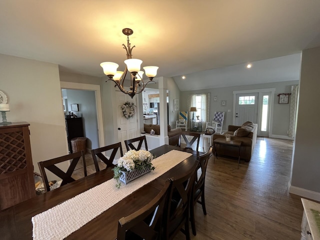 dining area with vaulted ceiling, an inviting chandelier, baseboards, and wood finished floors