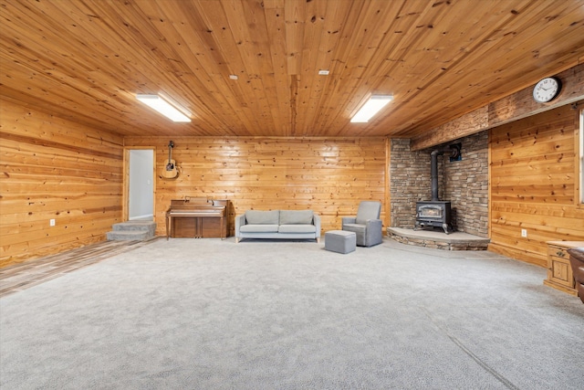 unfurnished room with a wood stove, carpet flooring, wooden walls, and wood ceiling