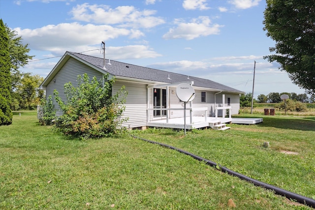 rear view of house with a deck, a shingled roof, and a lawn