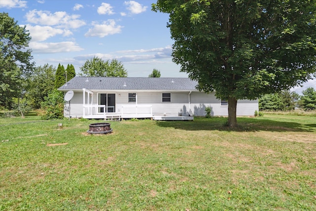 back of house featuring a yard, a deck, and a fire pit