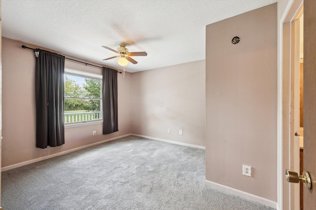 spare room featuring a textured ceiling, carpet floors, a ceiling fan, and baseboards