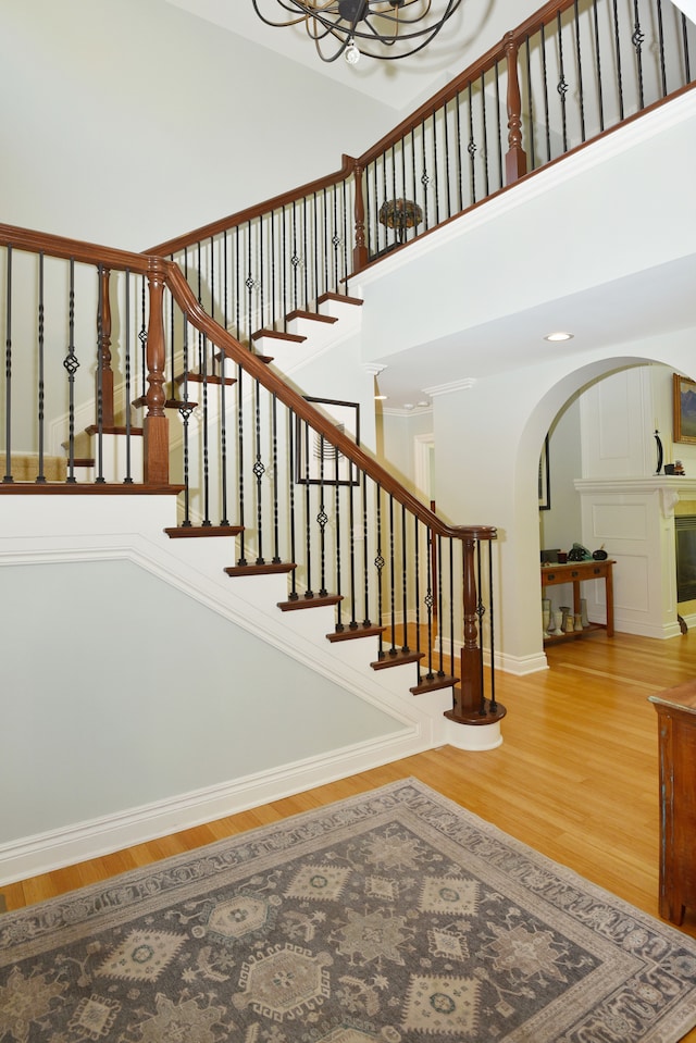 1256 Lenhill Ct, Bloomfield Hills, MI 48304 - stairway featuring arched walkways, wood finished floors, a high ceiling, a chandelier, and baseboards