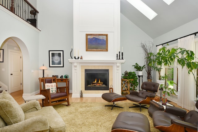 1256 Lenhill Ct, Bloomfield Hills, MI 48304 - living room featuring high vaulted ceiling, a skylight, a tiled fireplace, arched walkways, and wood finished floors