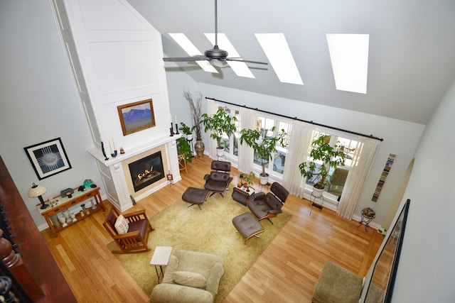 1256 Lenhill Ct, Bloomfield Hills, MI 48304 - living area featuring light wood-type flooring, a skylight, high vaulted ceiling, a glass covered fireplace, and ceiling fan