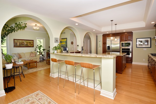 1256 Lenhill Ct, Bloomfield Hills, MI 48304 - kitchen with built in appliances, a breakfast bar area, light stone counters, light wood finished floors, and a peninsula