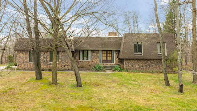 view of front of property featuring a front lawn, brick siding, roof with shingles, and a chimney