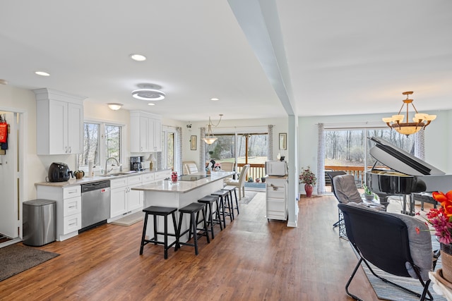 kitchen featuring dishwasher, a breakfast bar, a chandelier, light countertops, and white cabinets