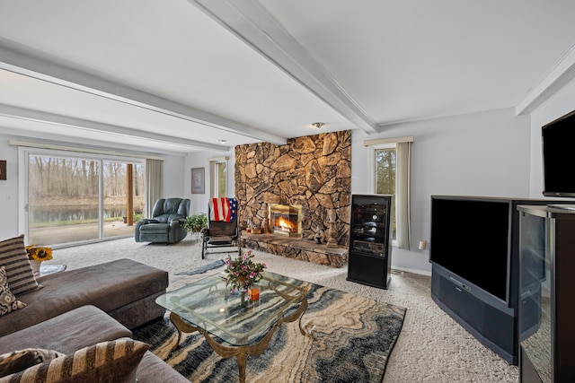 living area with a stone fireplace, beam ceiling, carpet, and a wealth of natural light