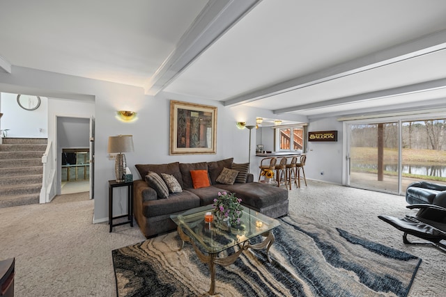 carpeted living room with baseboards, beamed ceiling, and stairway