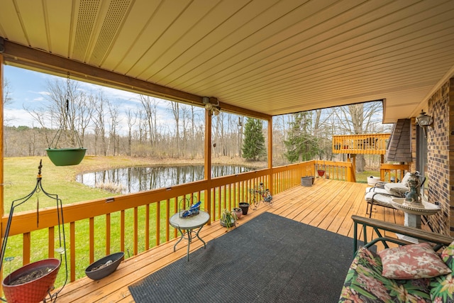 wooden deck featuring a water view and a lawn