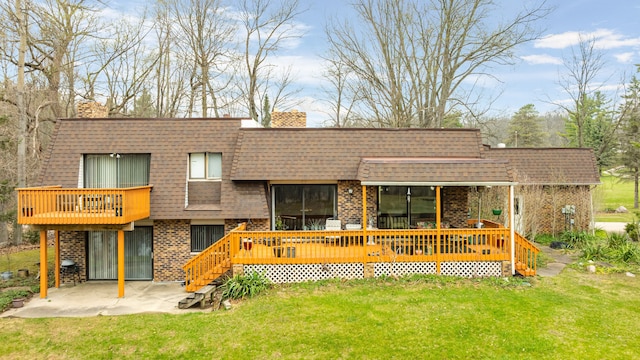 rear view of property with a lawn, a patio, brick siding, and a shingled roof
