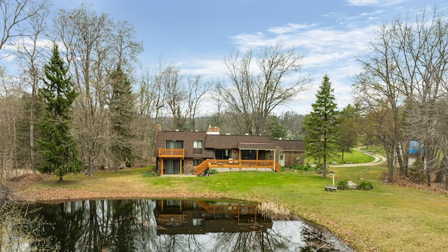 back of property featuring a lawn, a chimney, and a deck with water view
