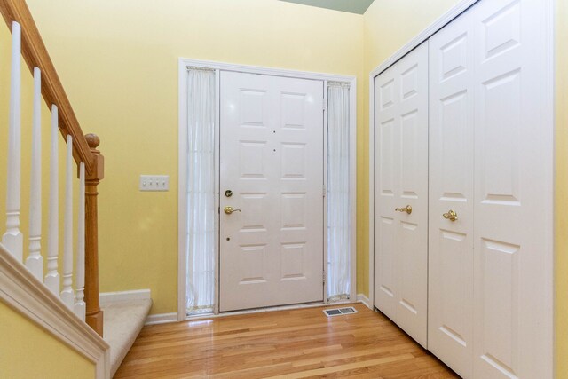 foyer featuring stairs, light wood-style floors, and baseboards