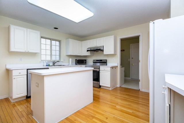 kitchen featuring stainless steel appliances, under cabinet range hood, light wood-type flooring, white cabinets, and a sink