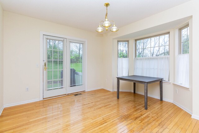 unfurnished dining area featuring a chandelier, light wood finished floors, and baseboards