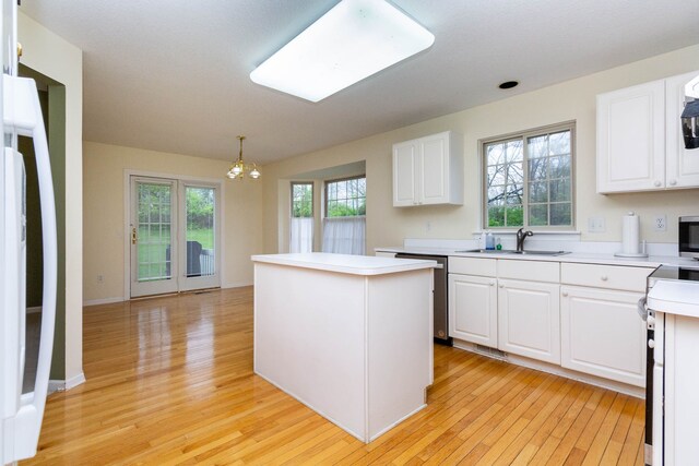 kitchen featuring a chandelier, a sink, light wood-type flooring, a center island, and white cabinets