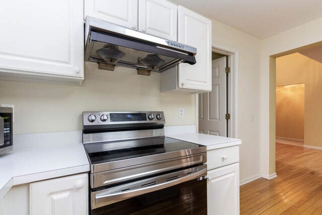 kitchen with electric stove, ventilation hood, and white cabinets