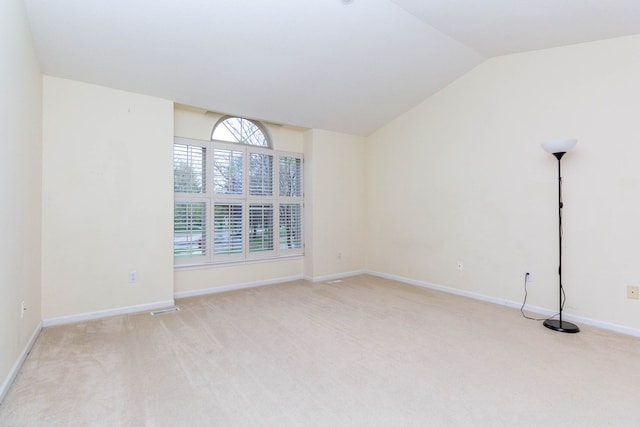unfurnished room with light carpet, lofted ceiling, and baseboards