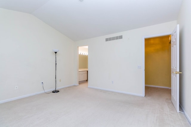 unfurnished bedroom featuring vaulted ceiling, light colored carpet, baseboards, and connected bathroom